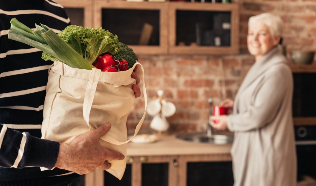 man holding grocery bag in kitchen