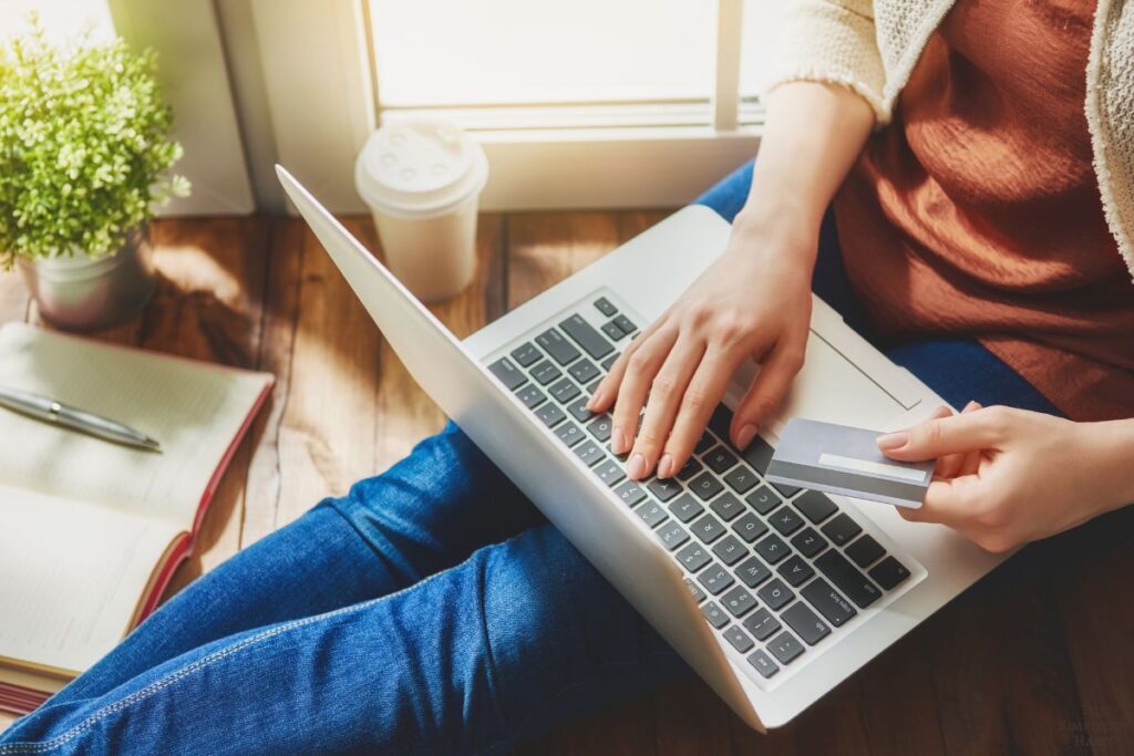 woman holding a credit card and typing on a laptop