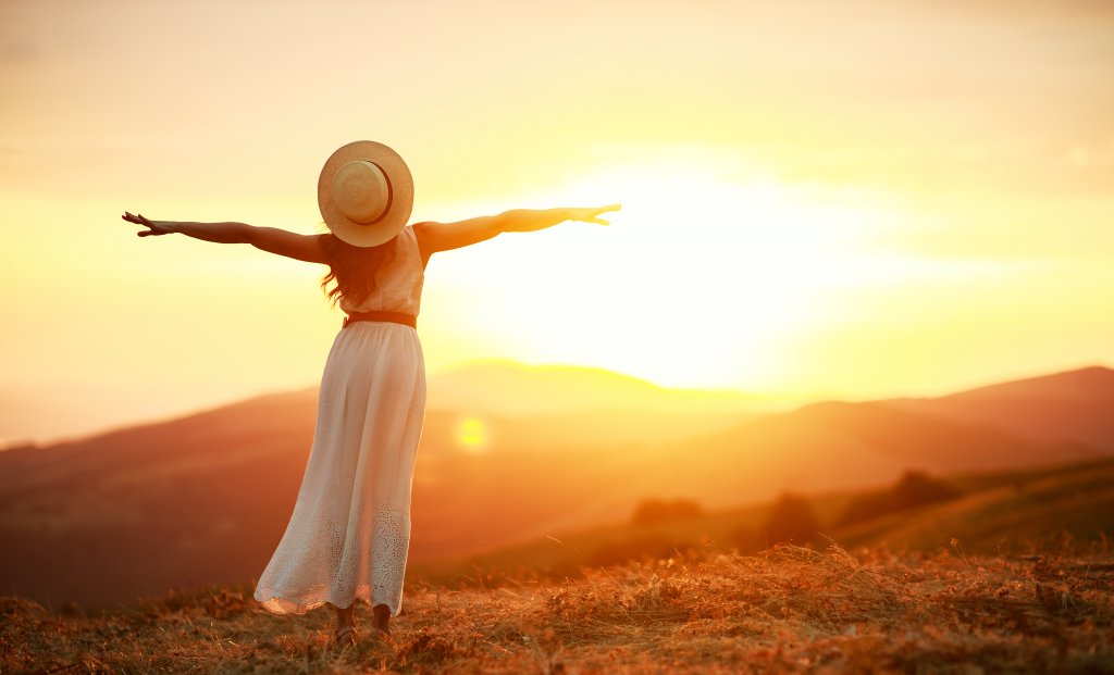 woman standing in a field with outstretched arms