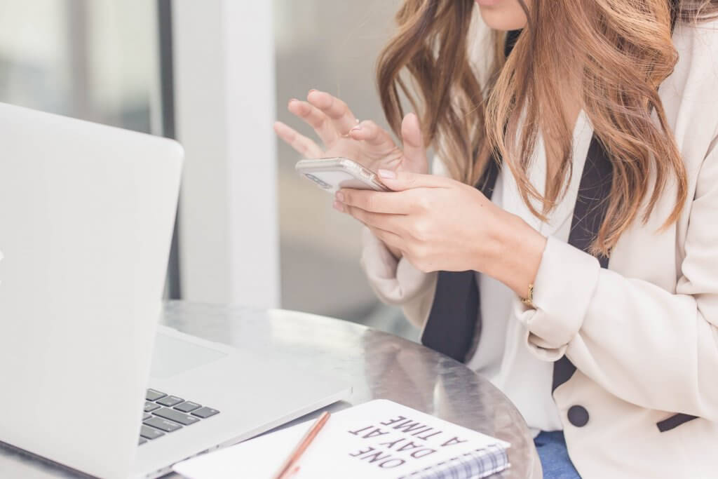 woman typing on phone at a table