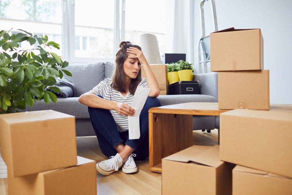 stressed woman looking at a receipt and surrounded by boxes