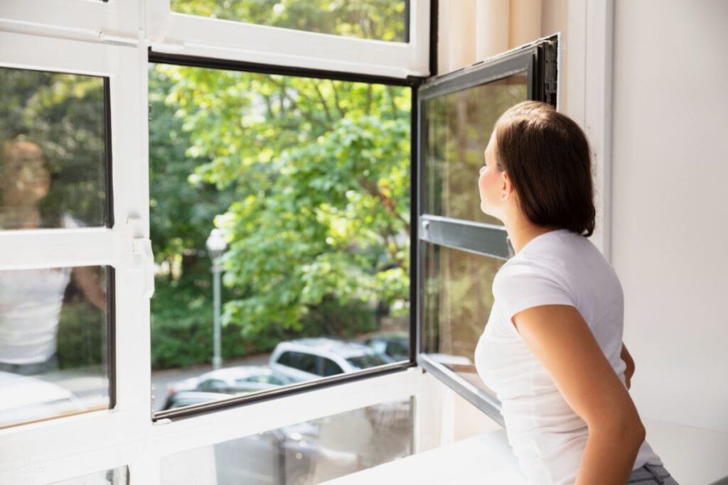 woman opening window in her home